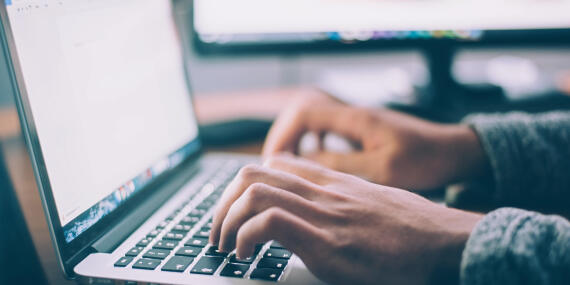 Mann tippt auf dem Laptop