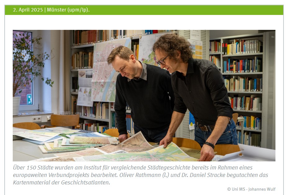 Zwei Mitarbeiter des IStG betrachten in der Instituts-Bibliothek großformatige Karten ihres Atlasprojektes