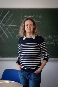 Zu sehen ist ein Porträt von Prof. Dr. Eva Viehmann vor einer Tafel im Hörsaal.<address>© NRW AWK | Bettina Engel-Albustin</address>